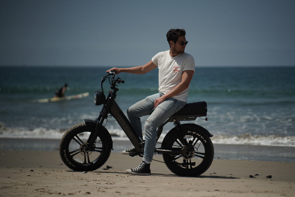 E-bike standing in front of ocean with a man wearing white t-shirt